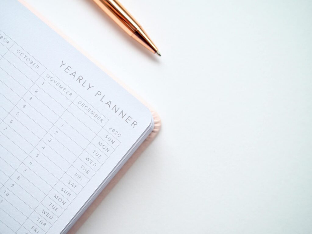 pexels-photo-1558691-1558691 A stylish yearly planner open to a 2020 calendar page, accompanied by a golden pen on a clean white surface.